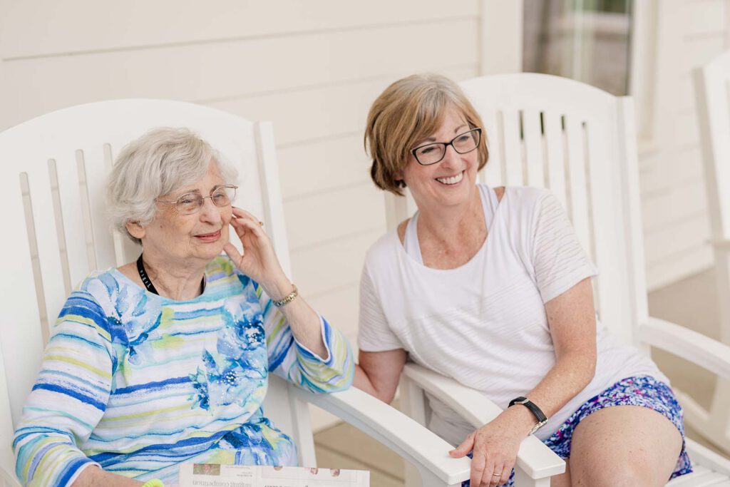 Senior woman and adult woman seated on patio